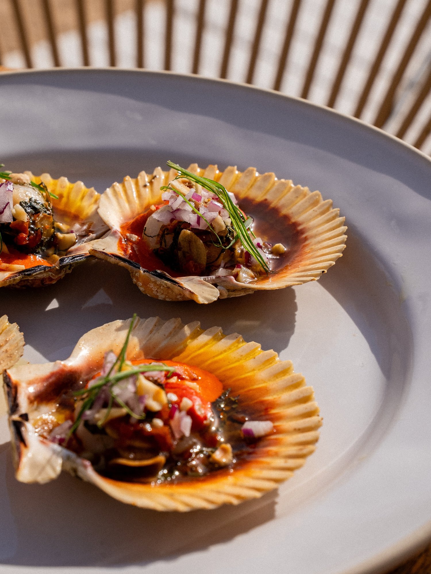Coquilles Saint-Jacques grillées, tomate, oignon rouge et pignons, servies en terrasse par Casa Pregonda à Ibiza