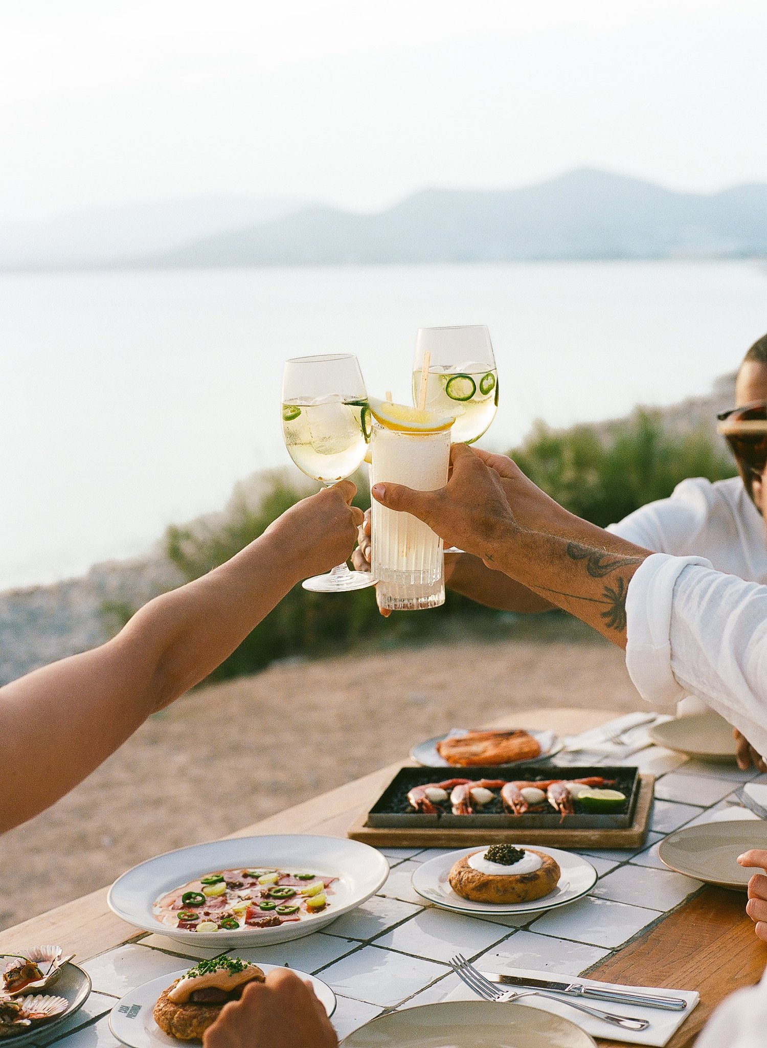 Des convives trinquent au-dessus d'une table de tapas face à la mer, Ibiza
