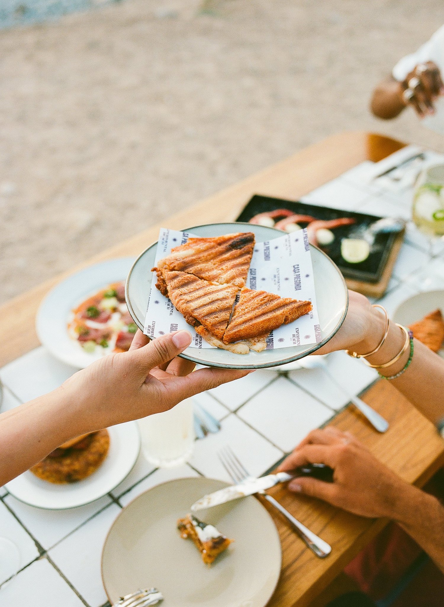 Une main tend une assiette de pain plat grillé au-dessus de la table, Casa Pregonda à Ibiza