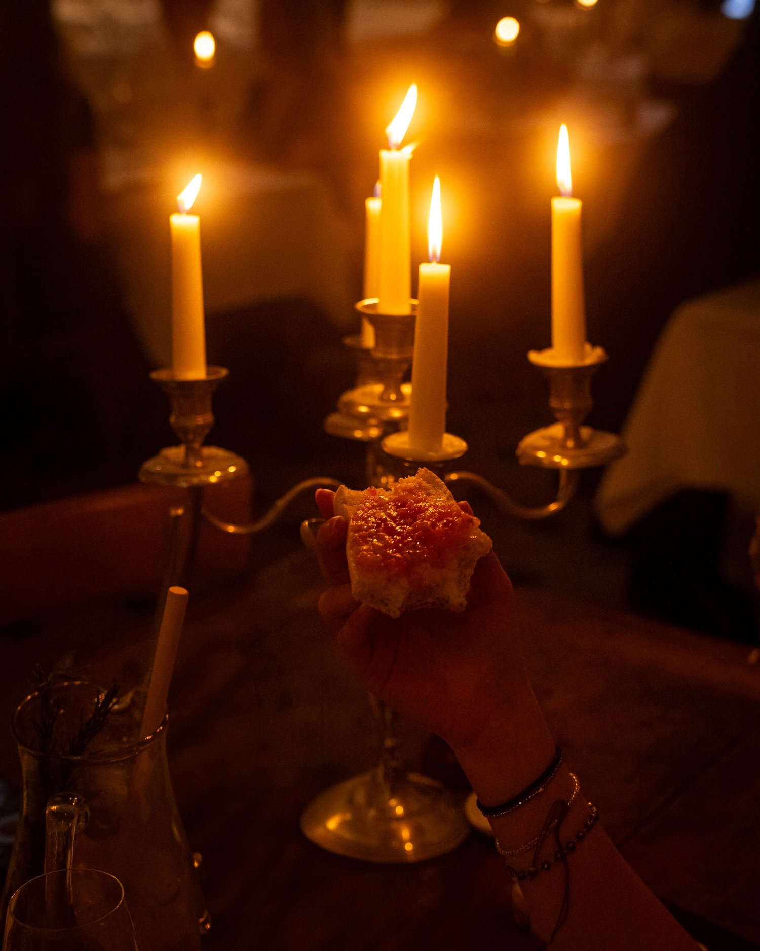 Une main lève un pan con tomate devant un chandelier, salle de Casa Pregonda, Paris
