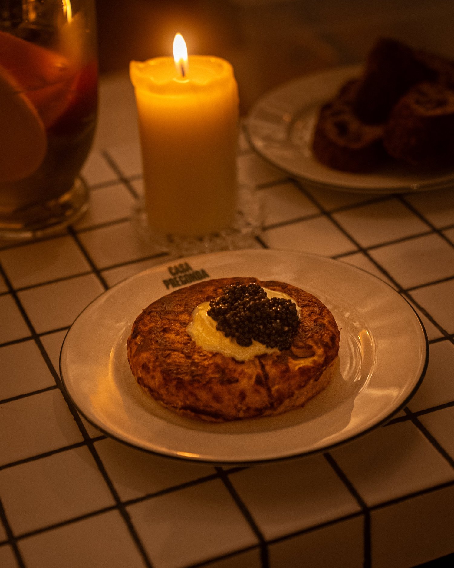 Beignet doré garni de crème et de caviar sur assiette Casa Pregonda, éclairé à la bougie