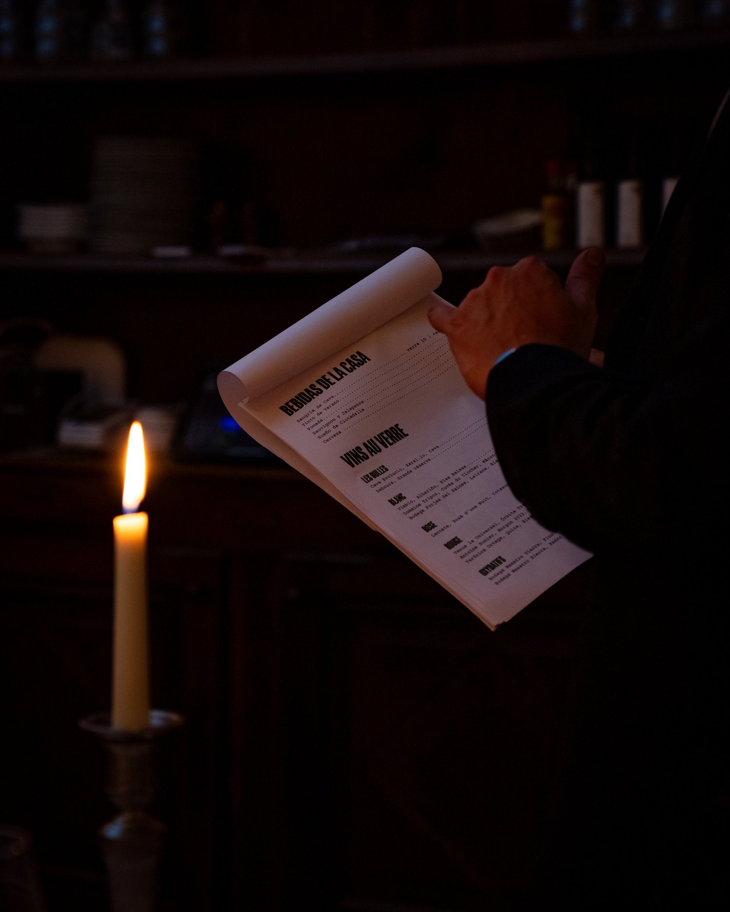 Un serveur parcourt la carte des boissons à la lueur d'une bougie, Casa Pregonda, Paris