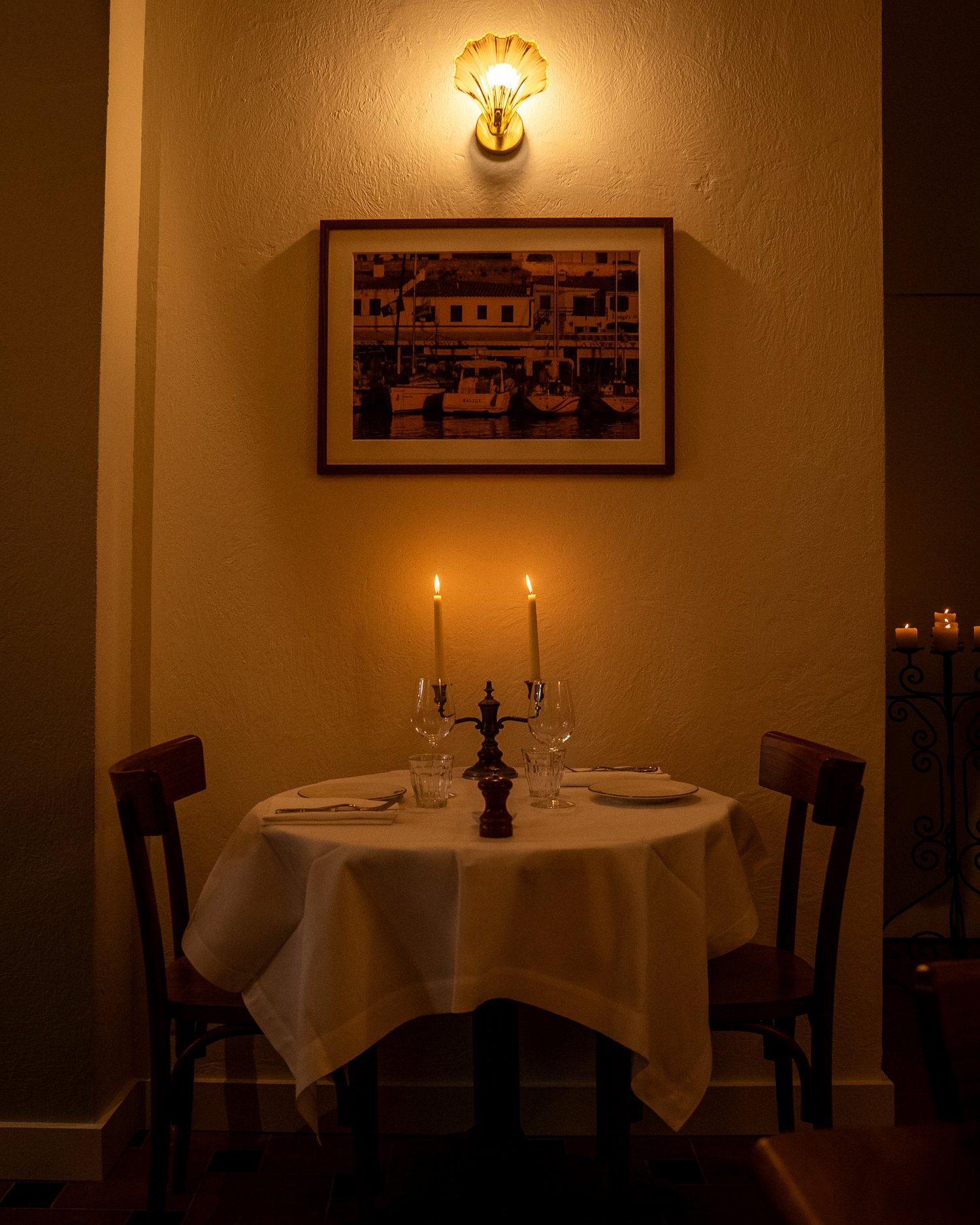 Table pour deux sous une photographie du port de Minorque, salle de Casa Pregonda, Paris