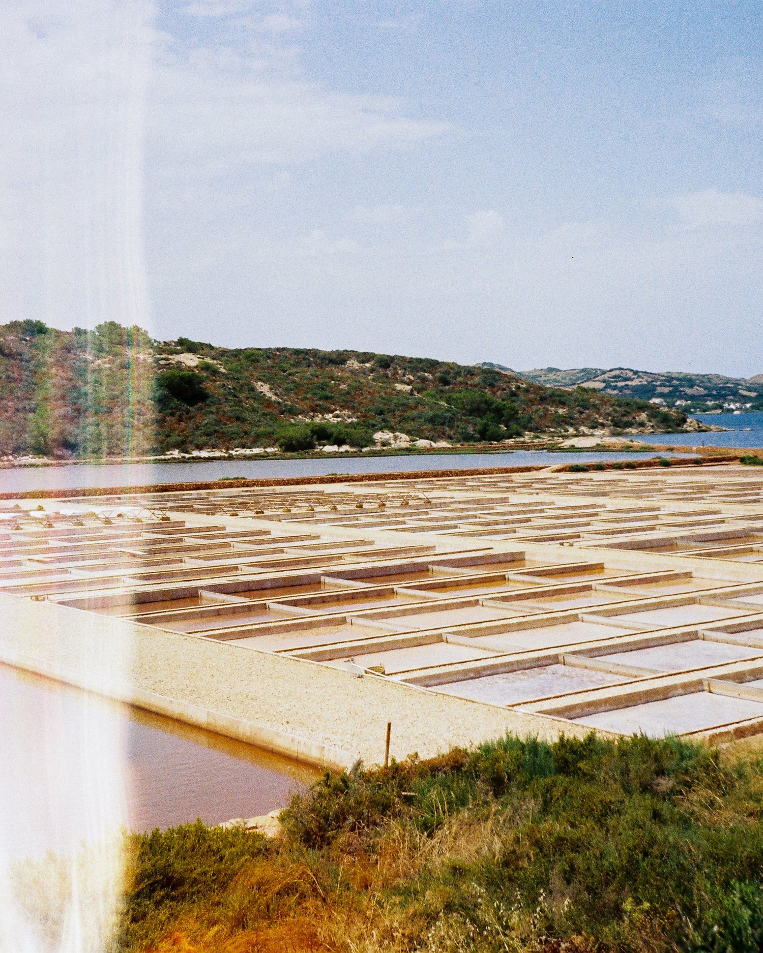 Bassins des salines alignés au bord de l'eau sous le ciel d'été, Minorque