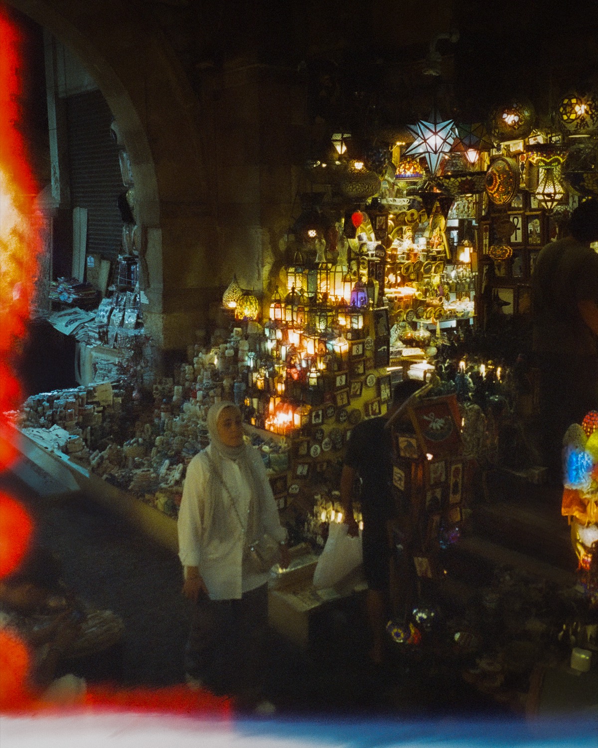Boutique de lanternes allumées dans le souk, une passante s'arrête devant l'étal, Le Caire