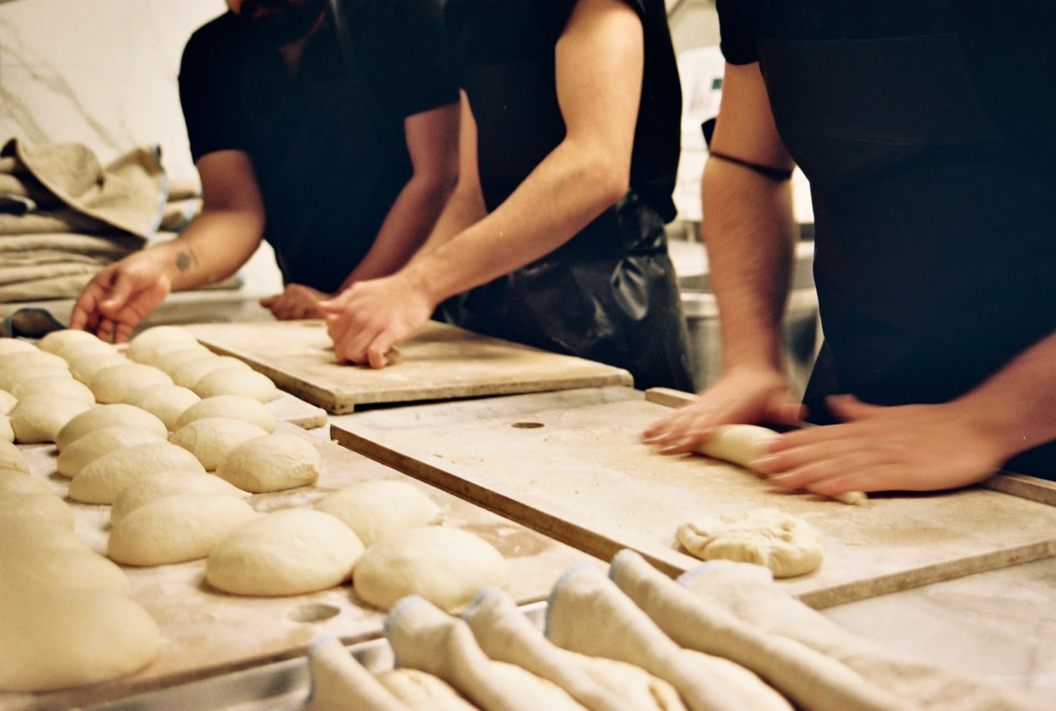 Trois paires de mains façonnent les pâtons au fournil, maison Cédric Grolet, Paris