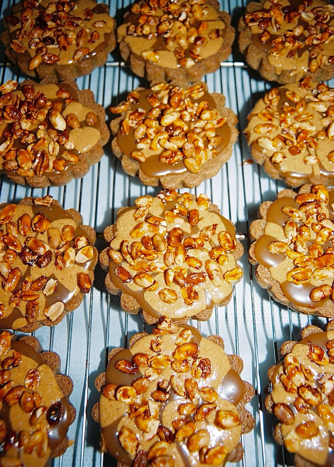 Tartelettes aux cacahuètes caramélisées alignées sur une grille, maison Cédric Grolet, Paris