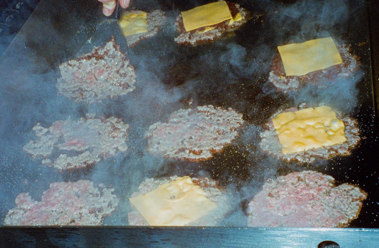 Steaks hachés écrasés et tranches de cheddar fondant sur la plancha fumante, Howard Original