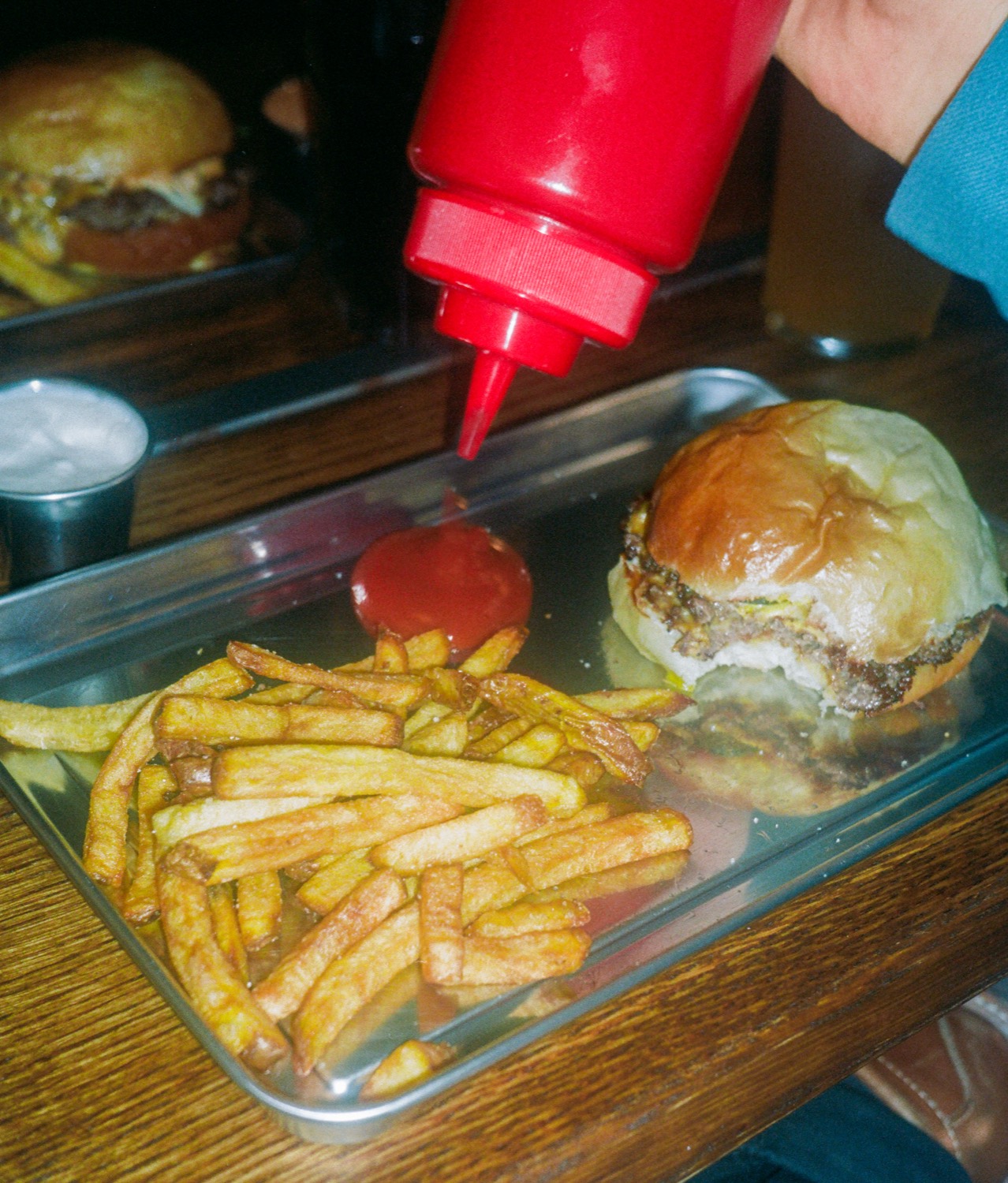 Une main presse le ketchup à côté d'un burger et de ses frites sur le plateau, Howard Original