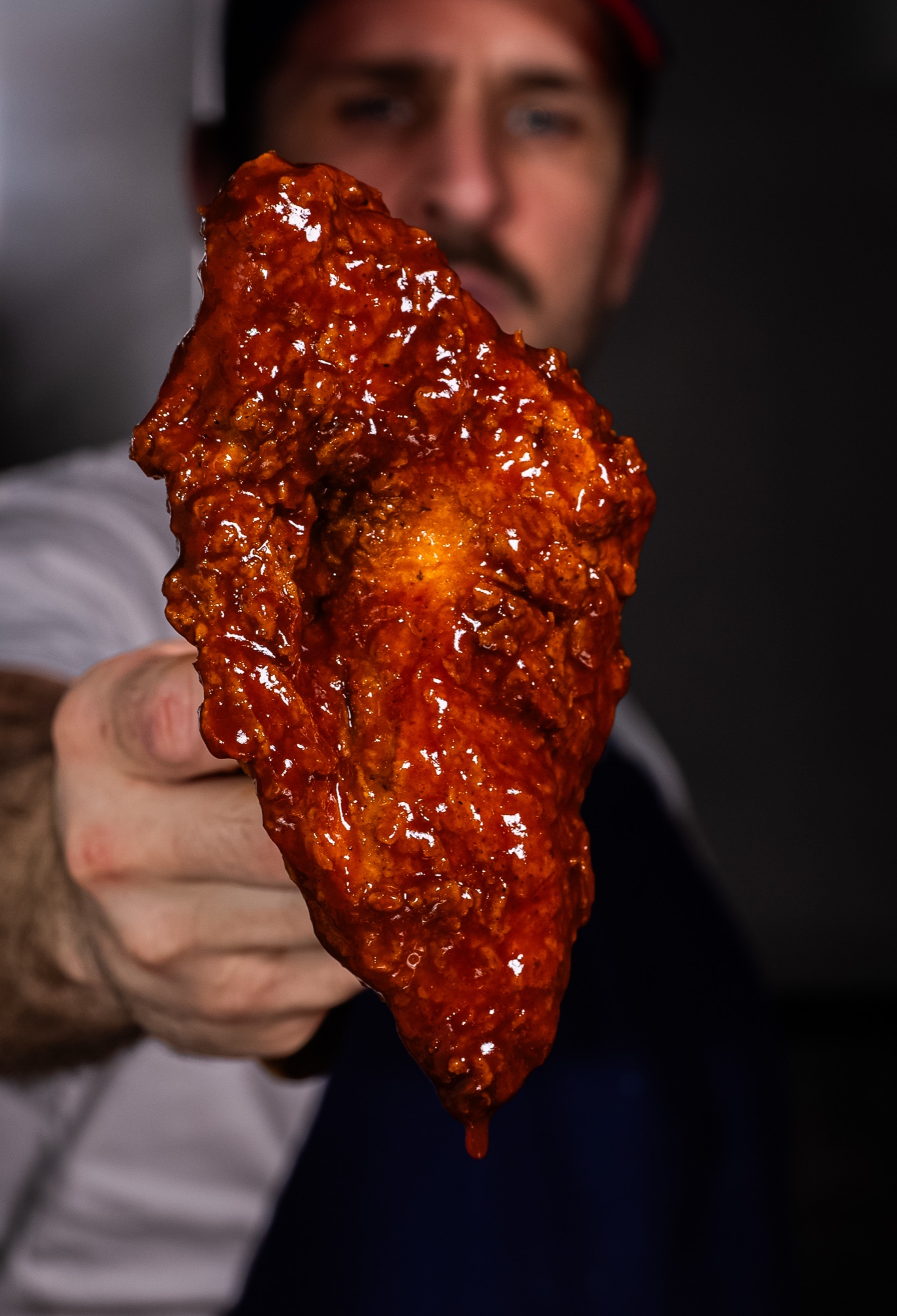 Un cuisinier tend un beignet de poulet laqué vers l'objectif, Howard Original
