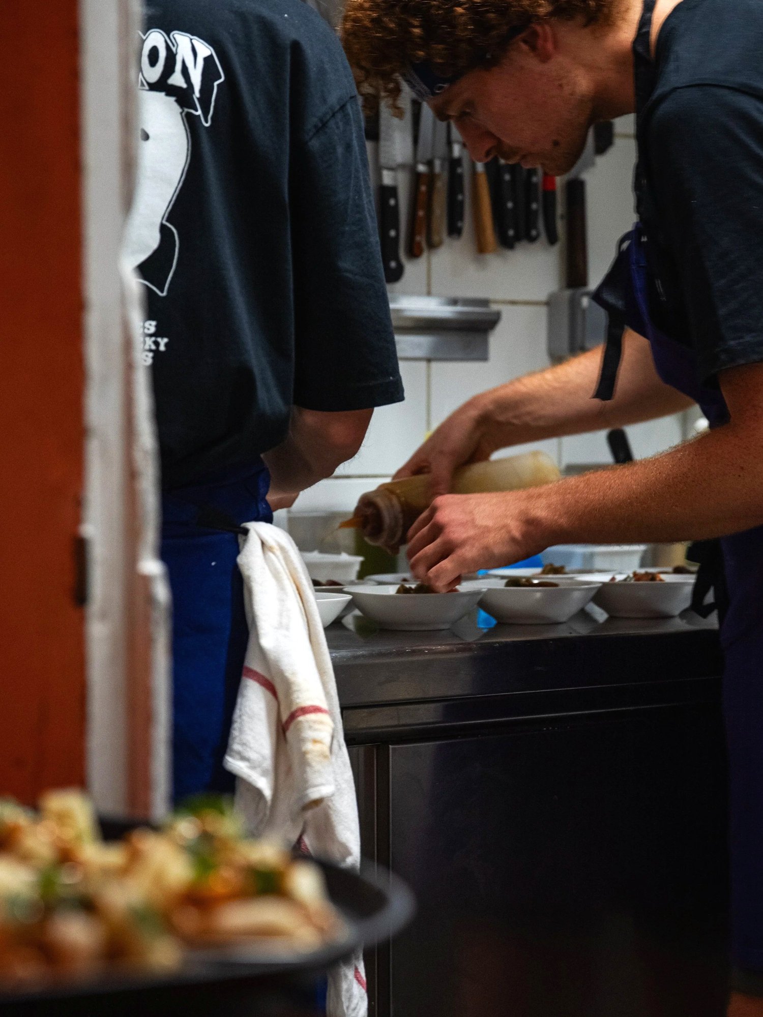 Un cuisinier assaisonne des bols sous la barre à couteaux, cuisine du Livingston, Marseille