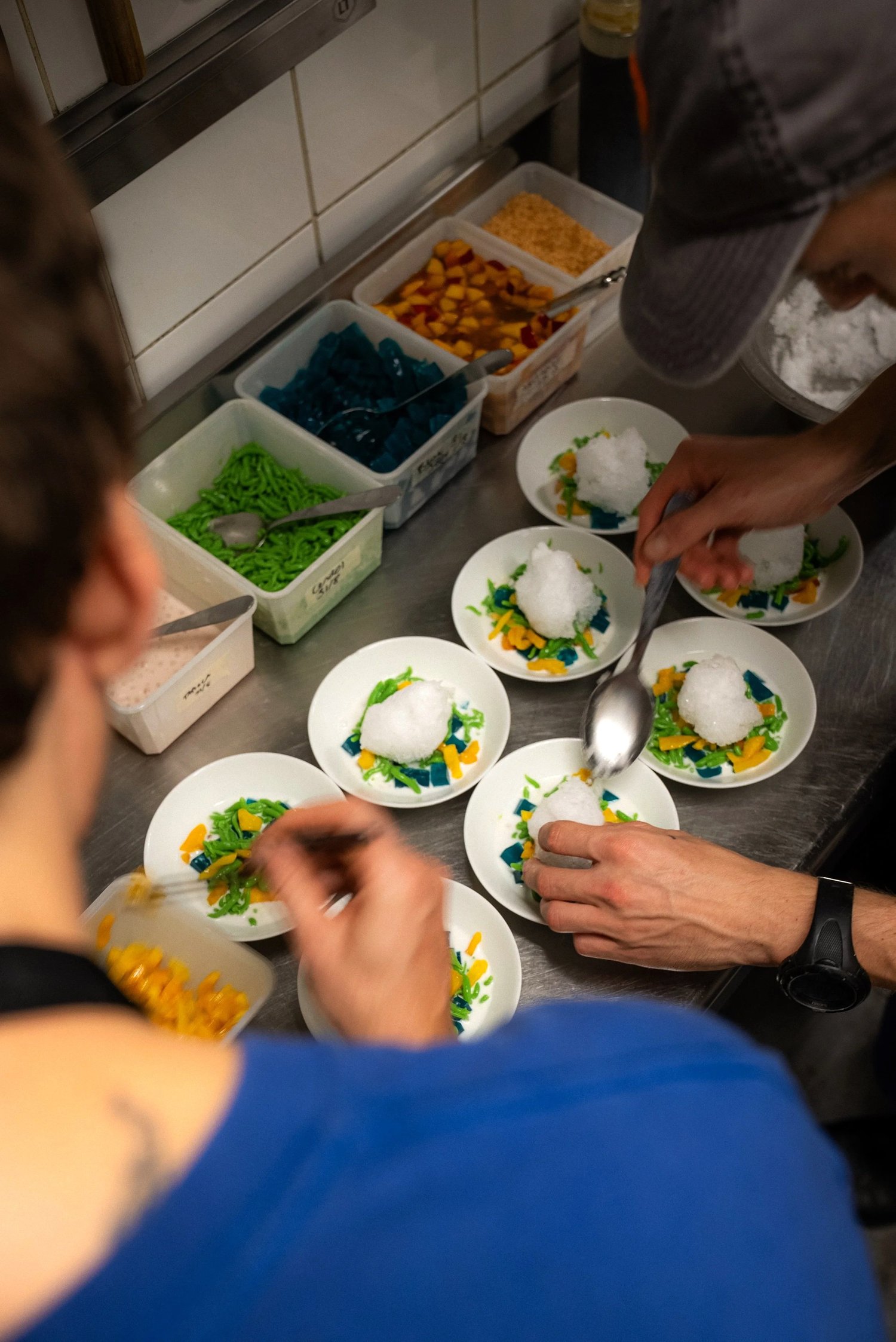 Deux cuisiniers dressent des assiettes colorées coiffées d'une neige glacée, cuisine du Livingston