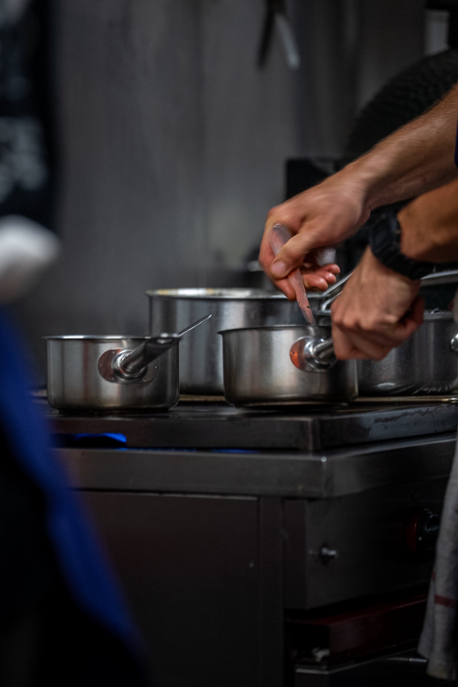 Des mains remuent de petites casseroles sur le piano, cuisine du Livingston à Marseille