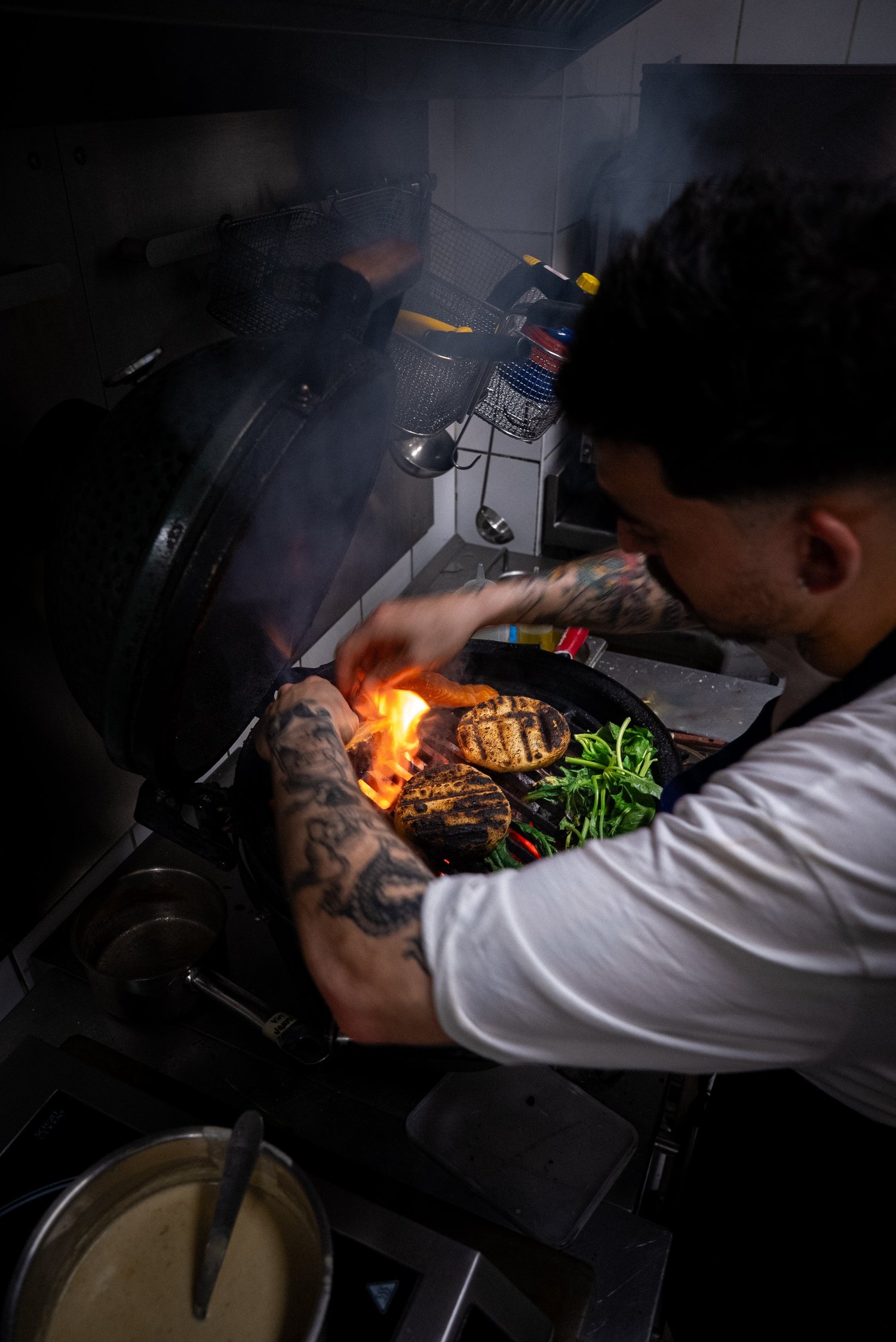 Un cuisinier saisit des légumes dans une poêle enflammée, cuisine du Livingston, Marseille