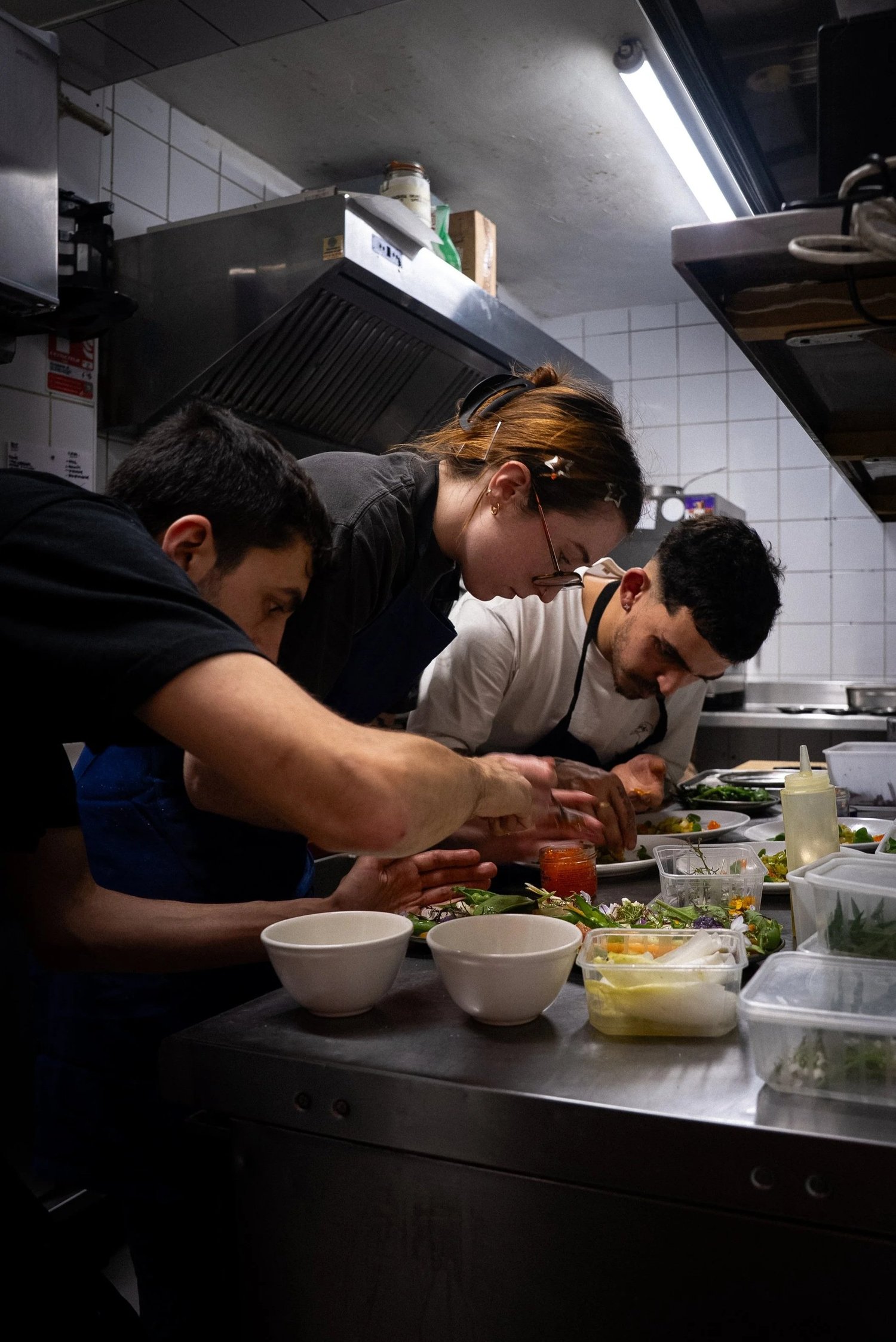 Trois cuisiniers penchés sur le passe pendant le dressage, Livingston, Marseille