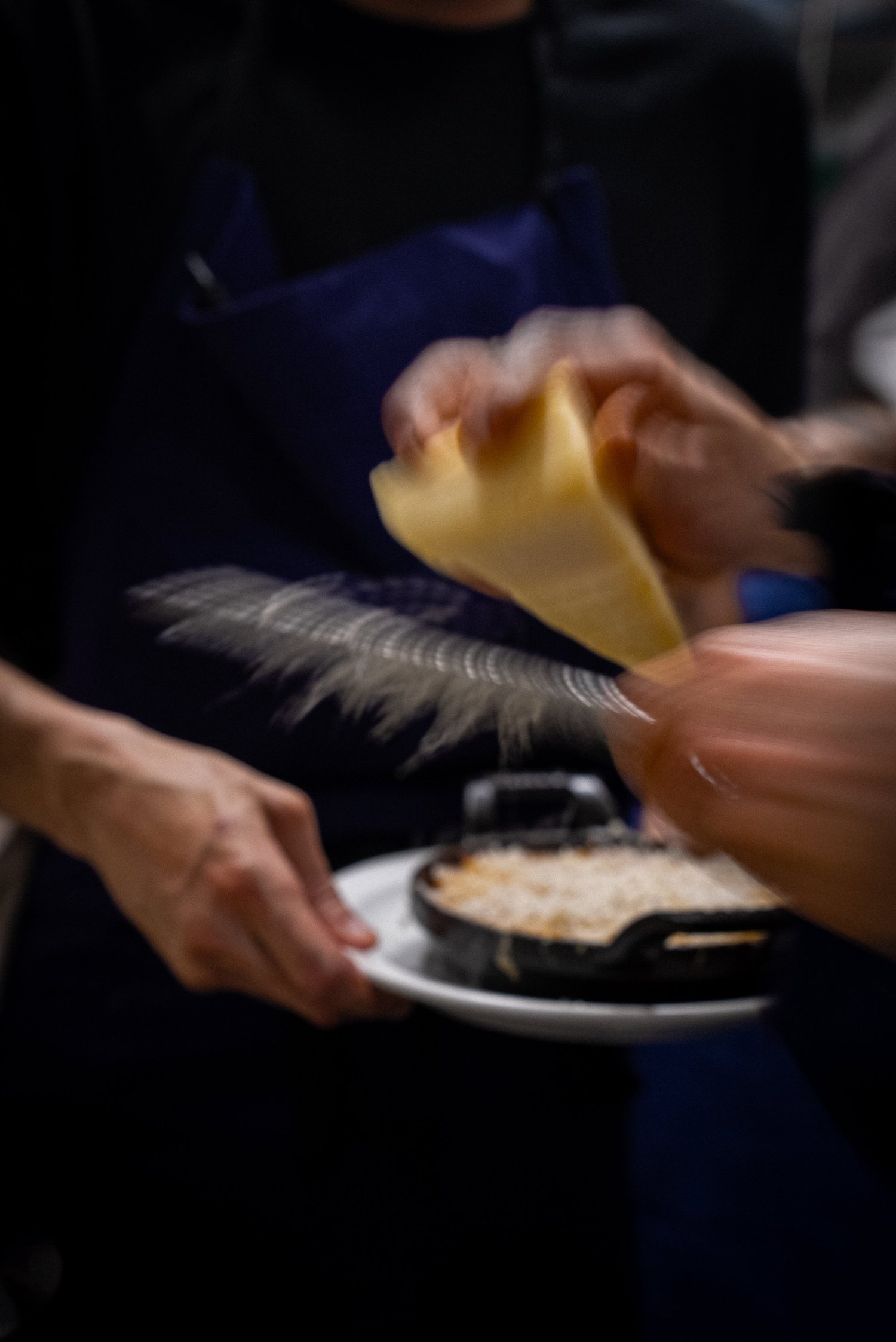 Du parmesan râpé en mouvement au-dessus d'un gratin dauphinois en cocotte, service au Livingston, Marseille