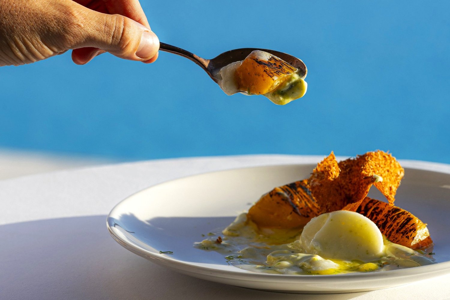 Une cuillère soulève une bouchée de melon grillé au-dessus du dessert, terrasse du Nhow, Marseille