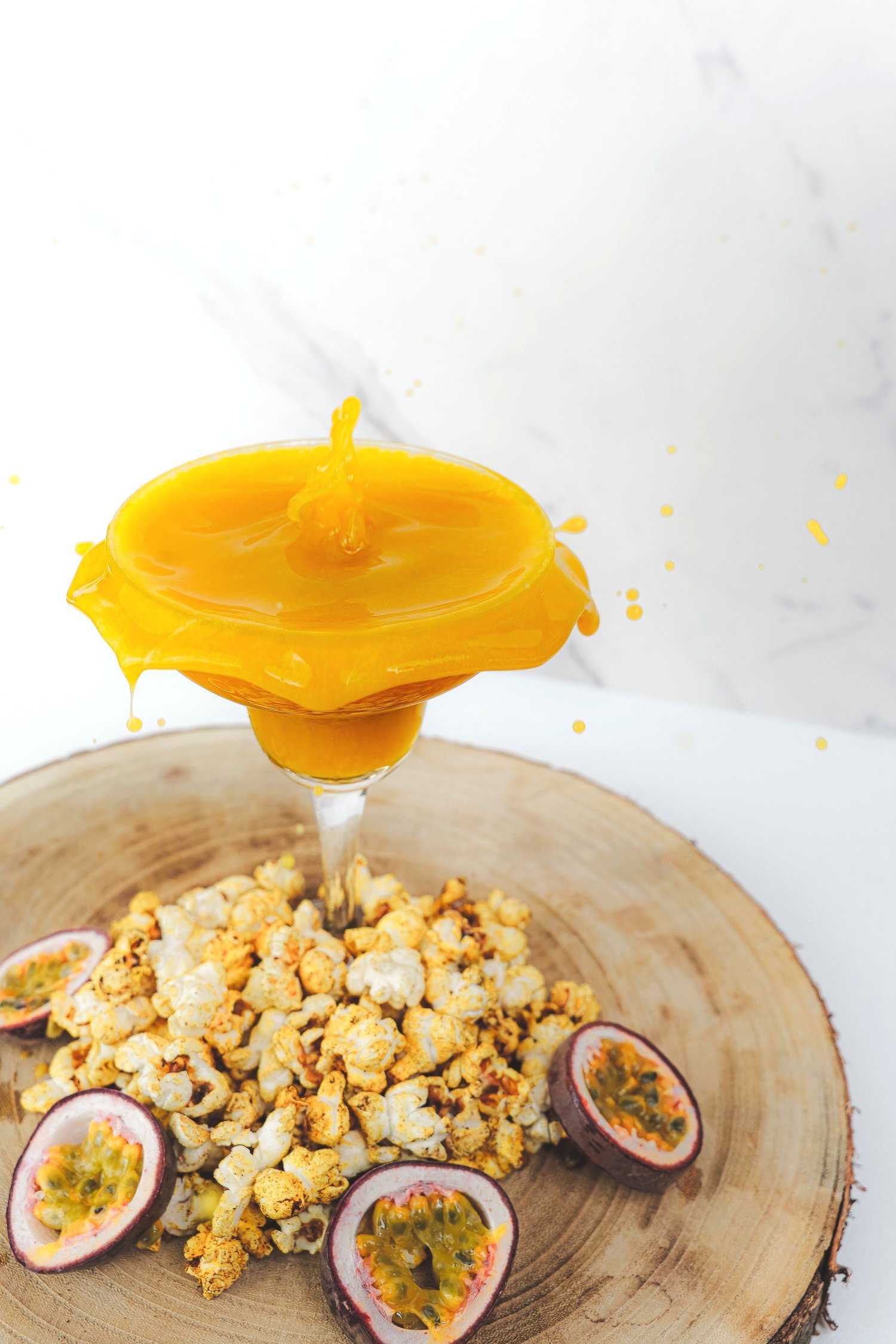 Cocktail jaune débordant de son verre au-dessus de pop-corn et de fruits de la passion, Nhow