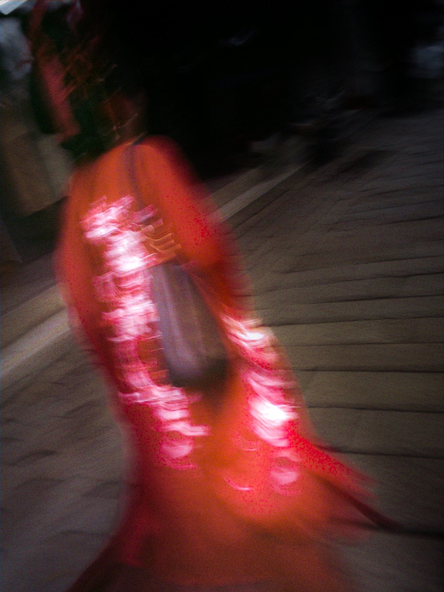 Silhouette floue d'une passante en robe rouge dans une rue le soir, filé de lumières, Shanghai