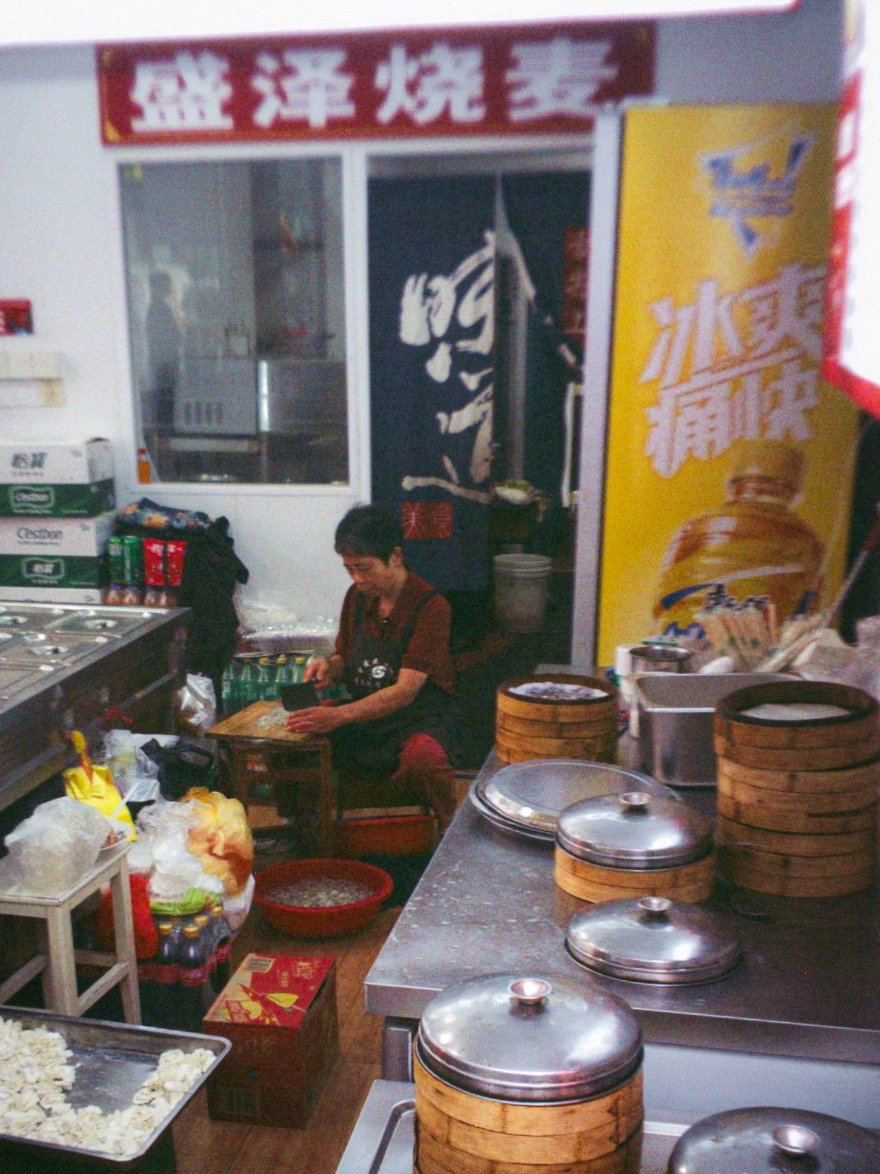 Une vendeuse prépare des bouchées vapeur derrière ses paniers de bambou, échoppe à l'enseigne chinoise, Shanghai