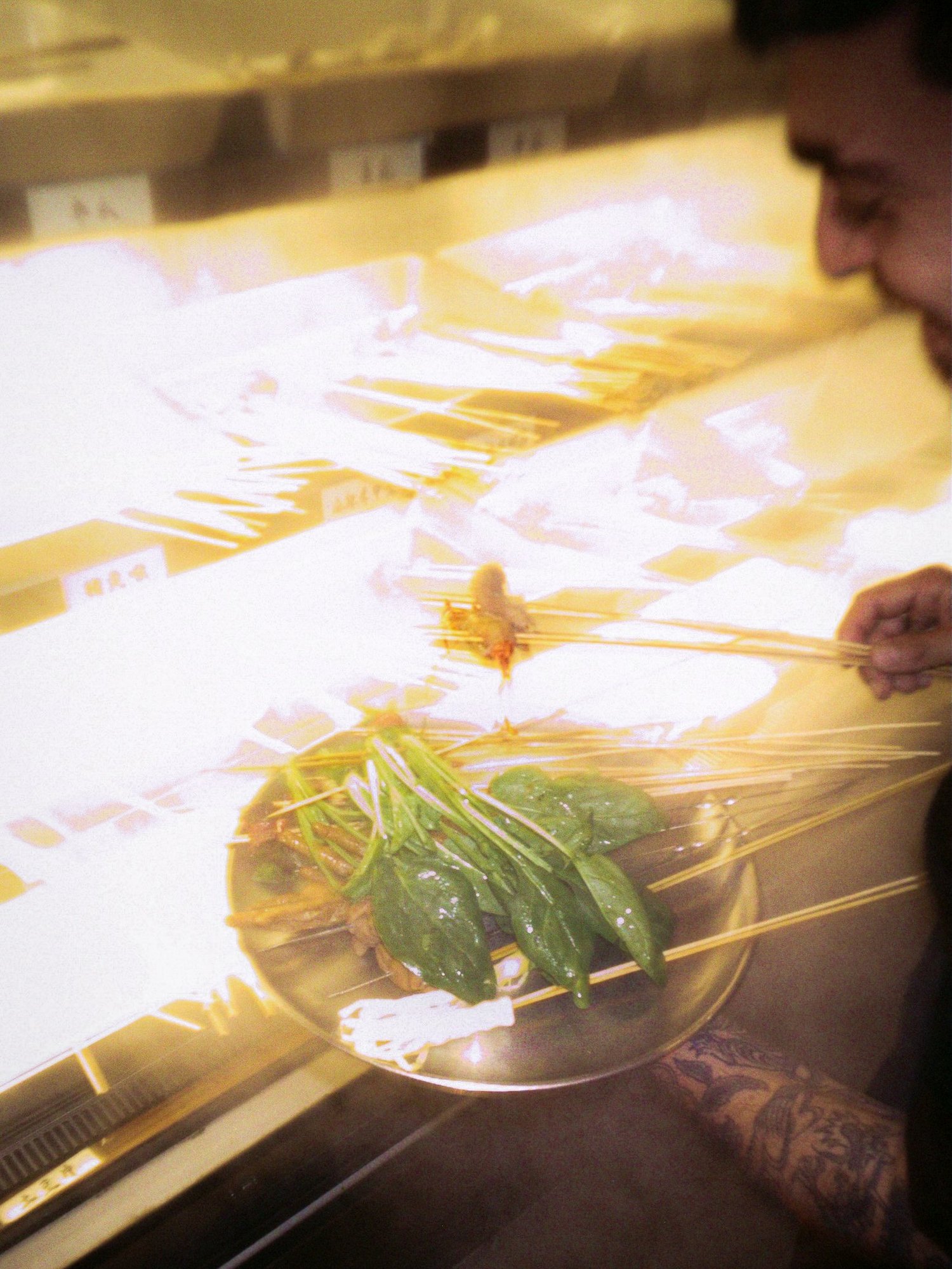 Un homme choisit des brochettes et des herbes au comptoir réfrigéré d'une échoppe de rue, Shanghai