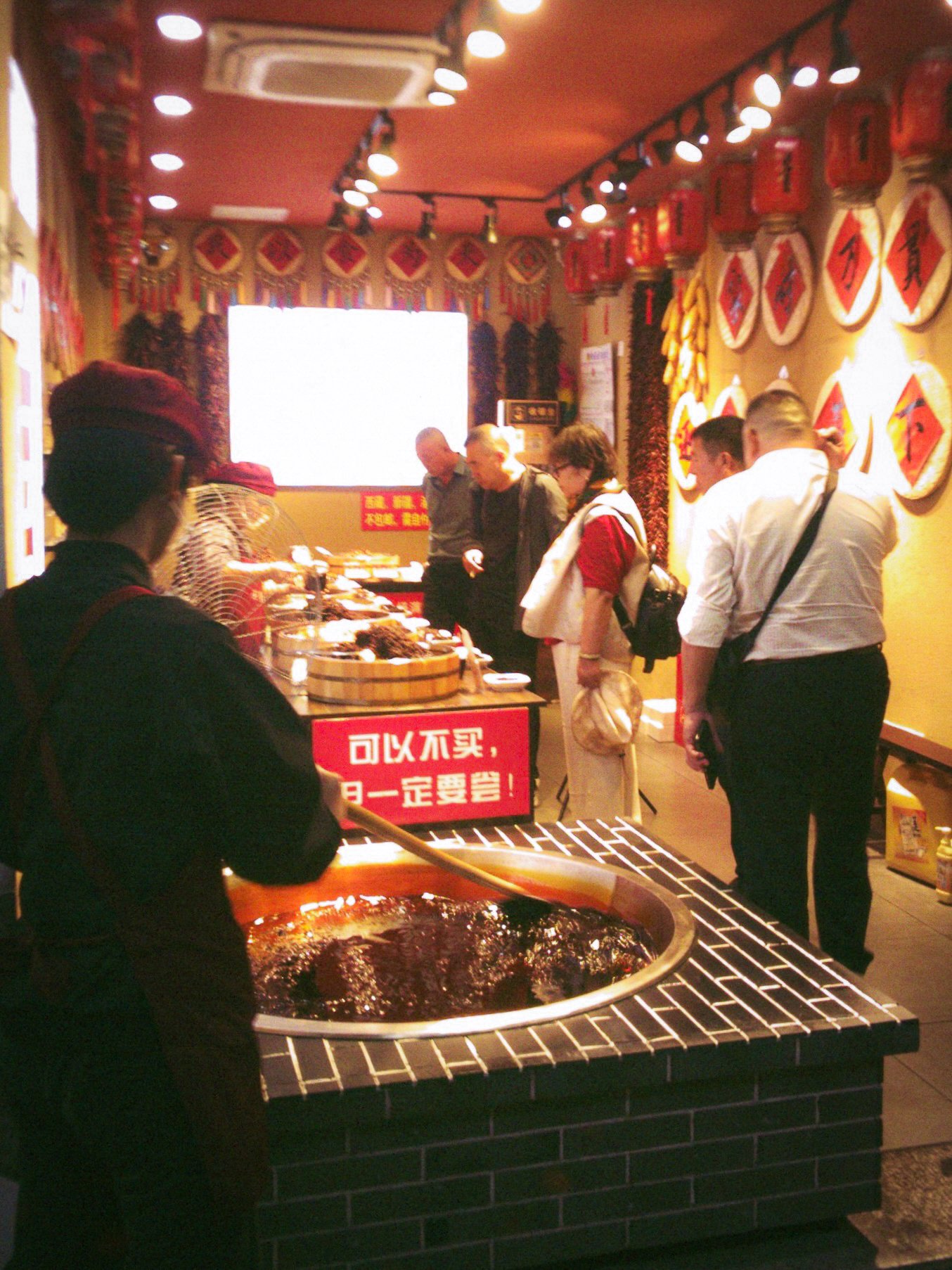 Boutique aux lanternes rouges où une vendeuse puise dans une grande cuve, clients en train de choisir, Shanghai