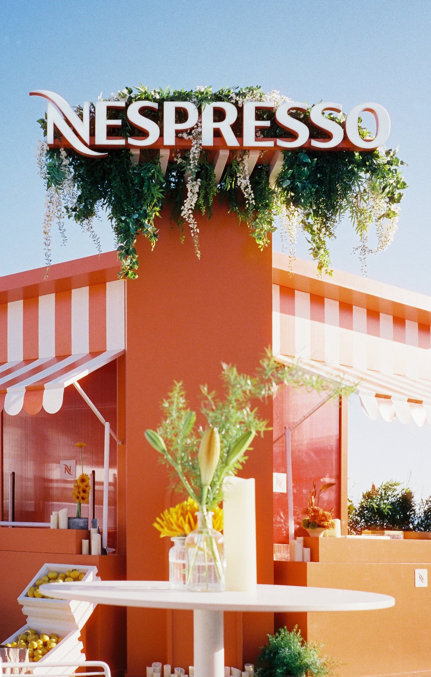 Stand Nespresso orange, fleuri et rayé de blanc sous le ciel bleu, Festival de Cannes