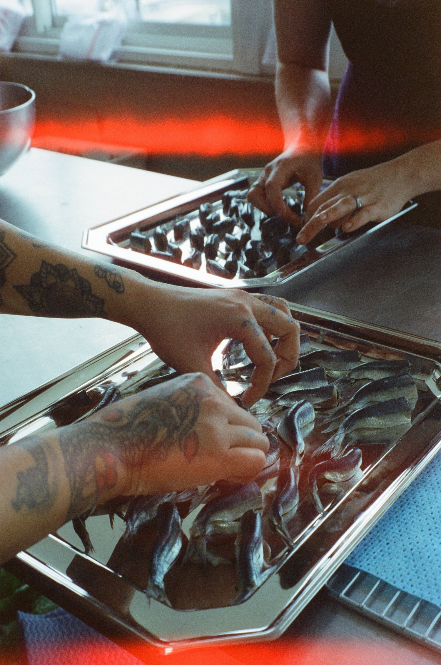 Des mains alignent les anchois sur des plateaux d'argent, préparation du dîner Chanel