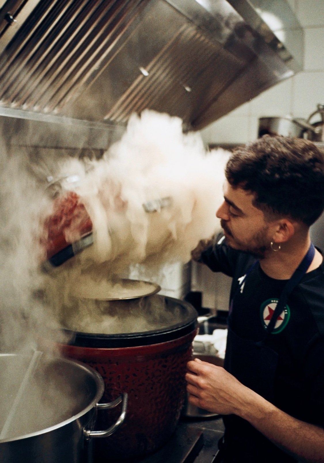 Un cuisinier verse une préparation fumante dans une grande marmite, cuisine du restaurant