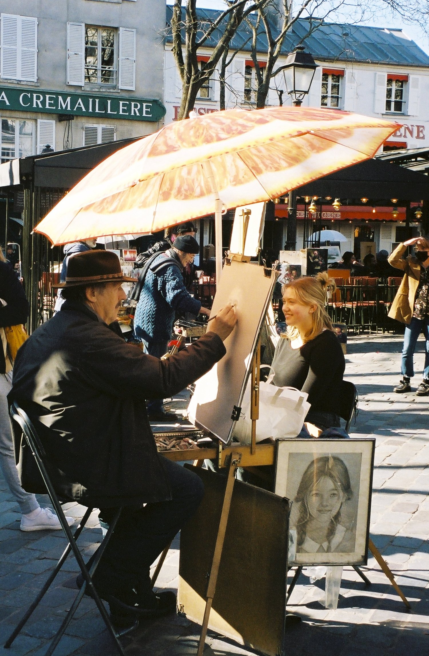 Un portraitiste dessine une cliente sous son parasol, place du Tertre, Paris