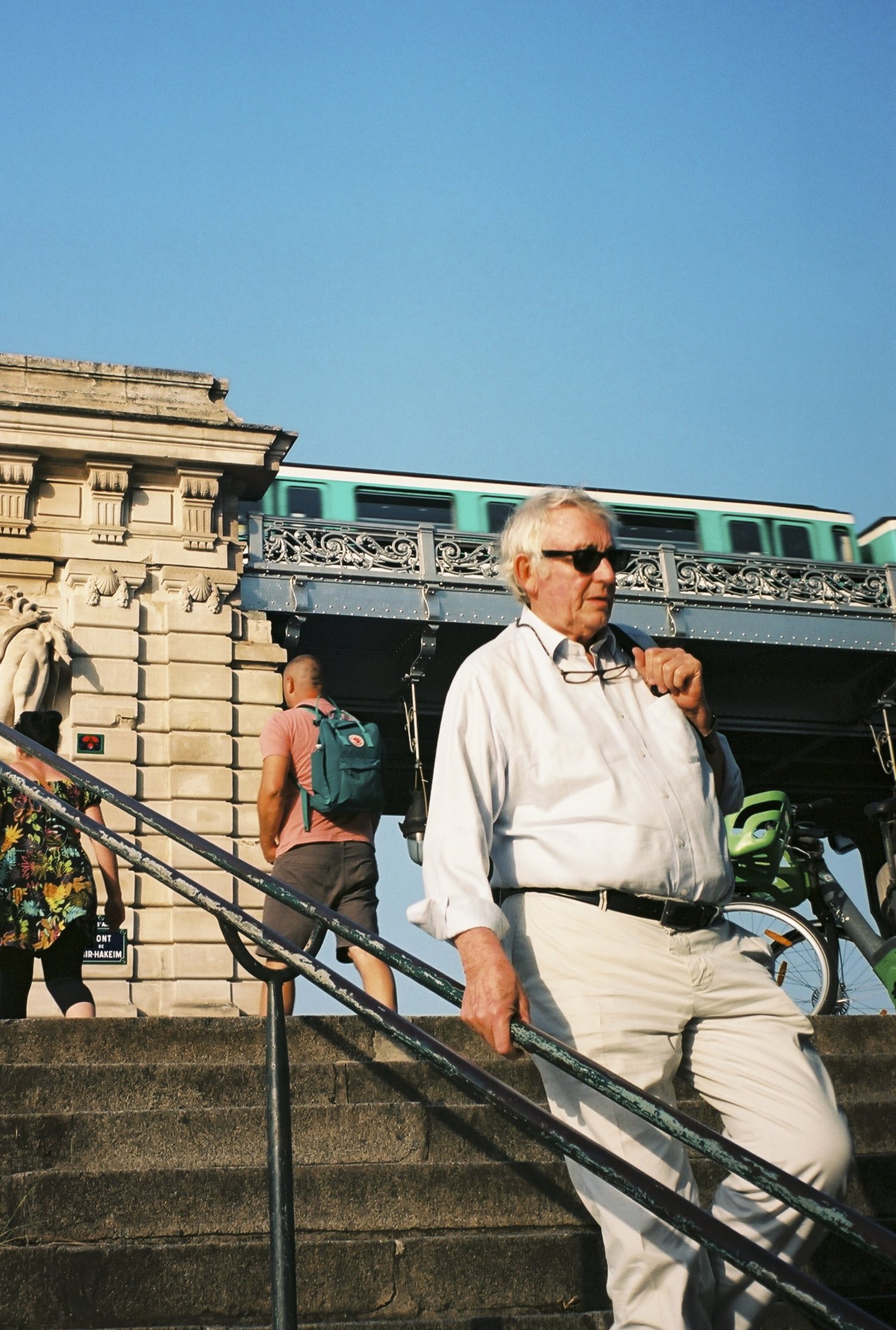 Un homme en chemise blanche descend l'escalier sous le métro aérien, Paris