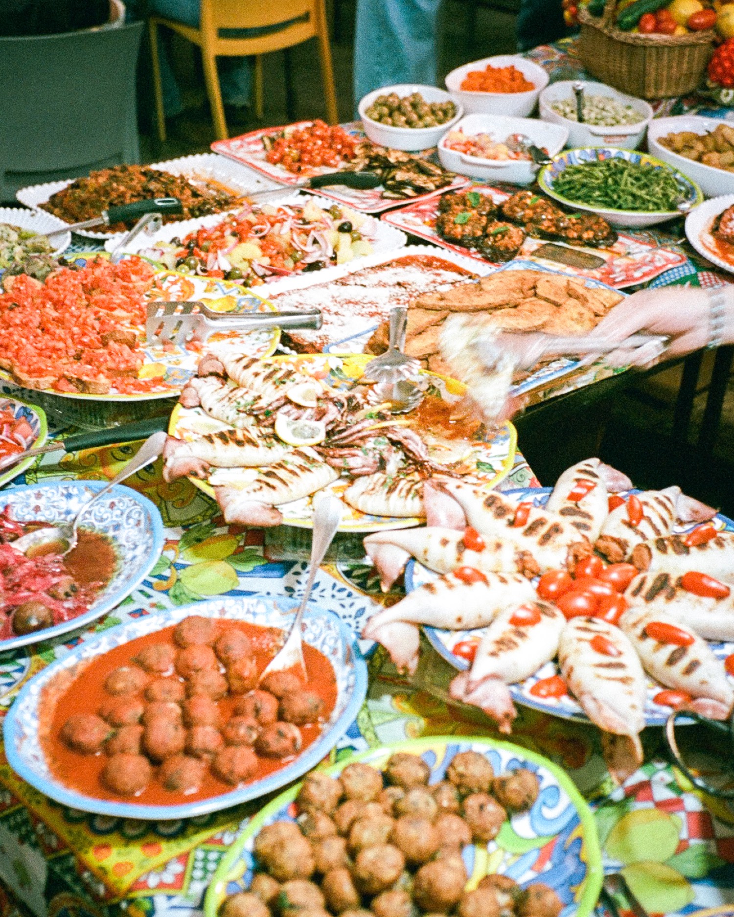 Étal de traiteur sicilien, calamars grillés, boulettes en sauce tomate, panelle et caponata